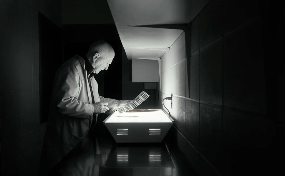 George Webber examining photographic negatives in the SAIT darkroom